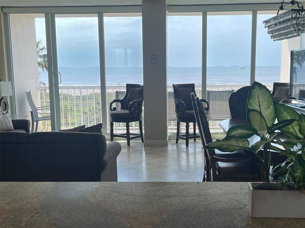 Spacious living area with large windows offering stunning ocean views. Features comfortable seating, a dining area, and abundant natural light, creating a bright and inviting atmosphere.