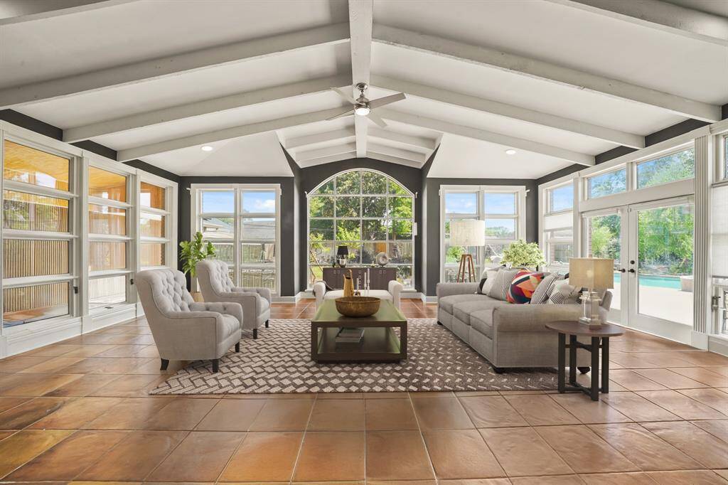 Virtually Staged: This living room is open and bright! Soaring high ceilings, a ceiling fan, tile flooring, recessed lighting, and plenty of natural light through the large wall of windows with a view of the backyard oasis!