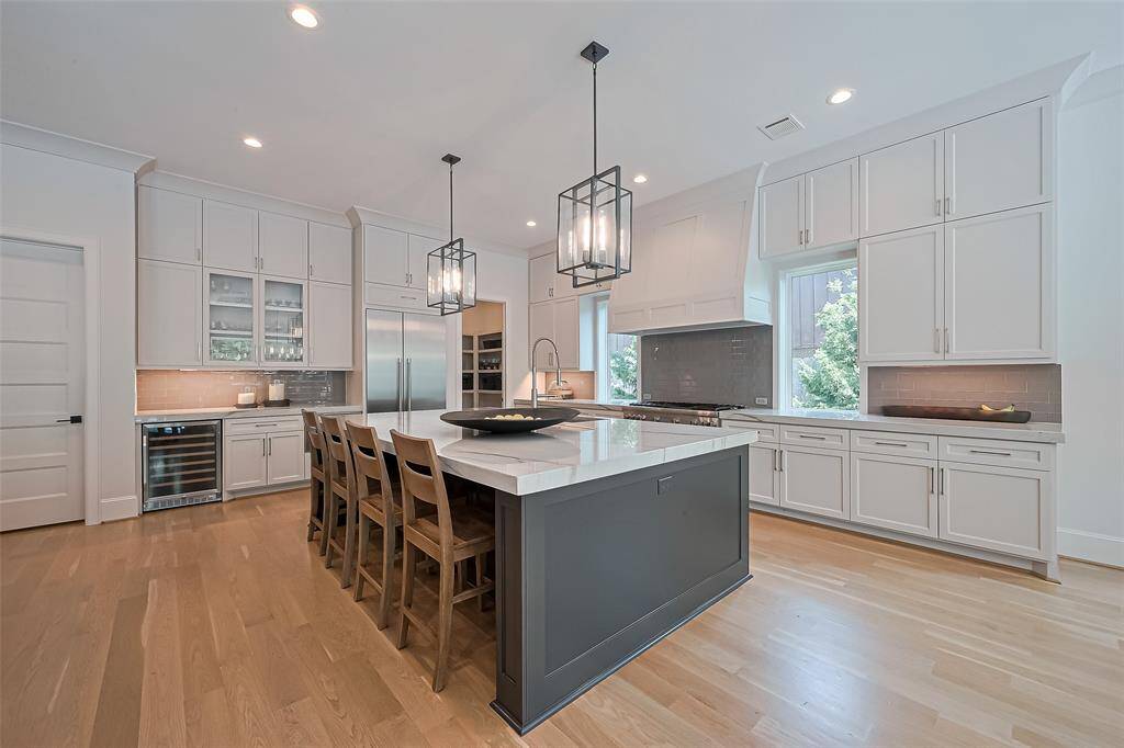 A view of the kitchen from the dining room, showcasing a spacious walk-in pantry located to the right of the refrigerator. The door on the left leads to the mudroom, utility room and the two-car garage.