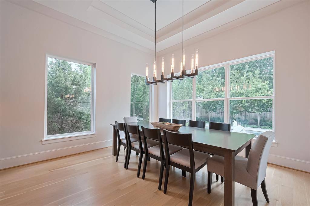 This bright and cheerful dining room offers a spacious feel, surrounded by windows that provide stunning views of the pool, backyard, and patio.