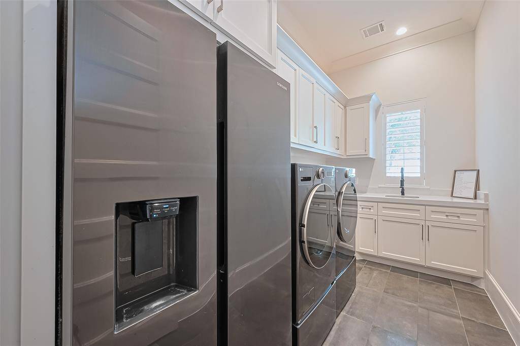 This home boasts a convenient and spacious utility room equipped with a sink and plenty of storage. Please note that the washer and dryer are not included in the sale, while the Samsung refrigerator is available for an additional purchase.
