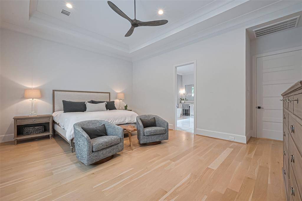 The primary suite, situated on the first floor, boasts a cozy sitting area and elegant high coffered ceilings adorned with crown molding.
