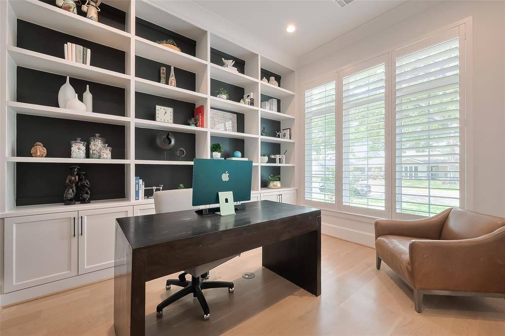 Situated at the front of the house, the bedroom/study/office features generous storage with built-in shelves and cabinets, all bathed in natural light.