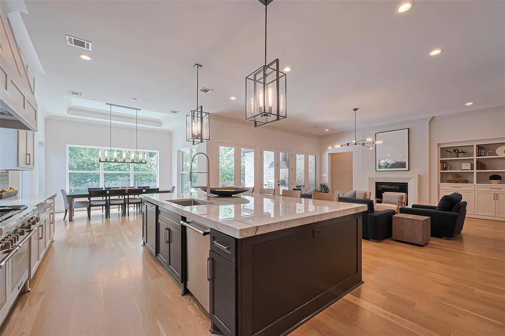 This kitchen is a dream come true for food enthusiasts and entertainers alike, showcasing Quartz countertops, Thermador appliances, a built-in refrigerator, wine cooler, and custom cabinets, all adjacent to a formal and spacious dining room.