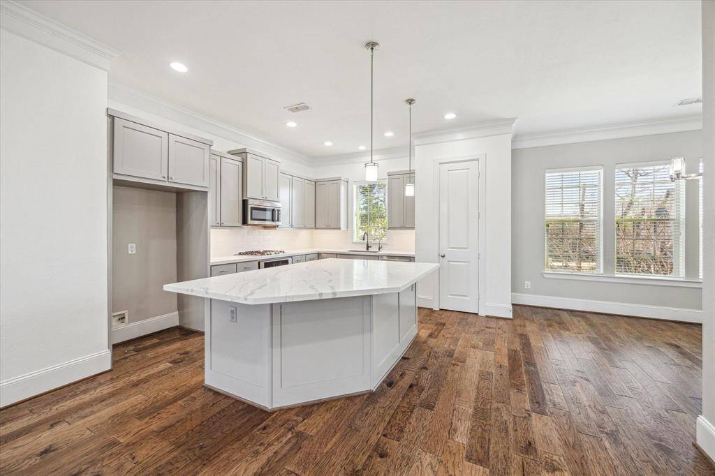 This beautifully designed kitchen is a chef’s dream, featuring stylish cabinetry with modern hardware, luxurious quartz countertops, sleek subway tile backsplash, and stainless steel appliances. The expansive island, with chic pendant lighting overhead and stunning waterfall edges, offers ample prep space and serves as a striking focal point for both cooking and entertaining.