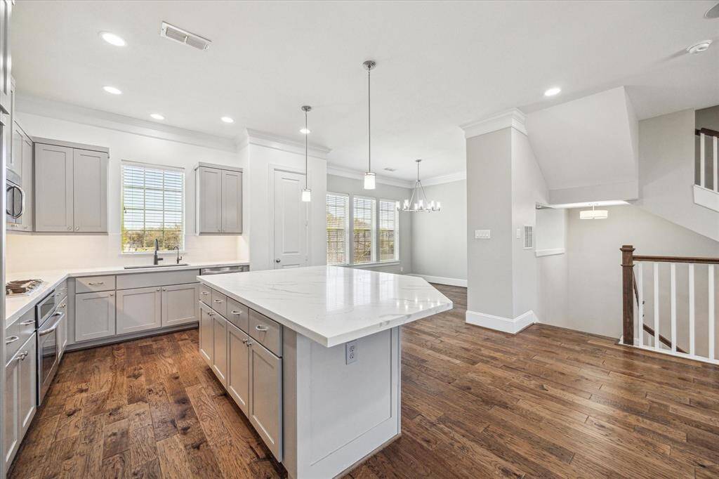 Show off your culinary skills in this stunning island kitchen with Quartz countertops, designer tile backsplash, under-cabinet lights, sleek stainless steel appliances, and stylish lighting over the island.