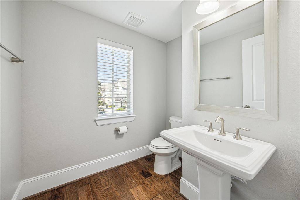 The powder bath is convenient for guests with a pedestal sink, framed mirror and vanity lights above.