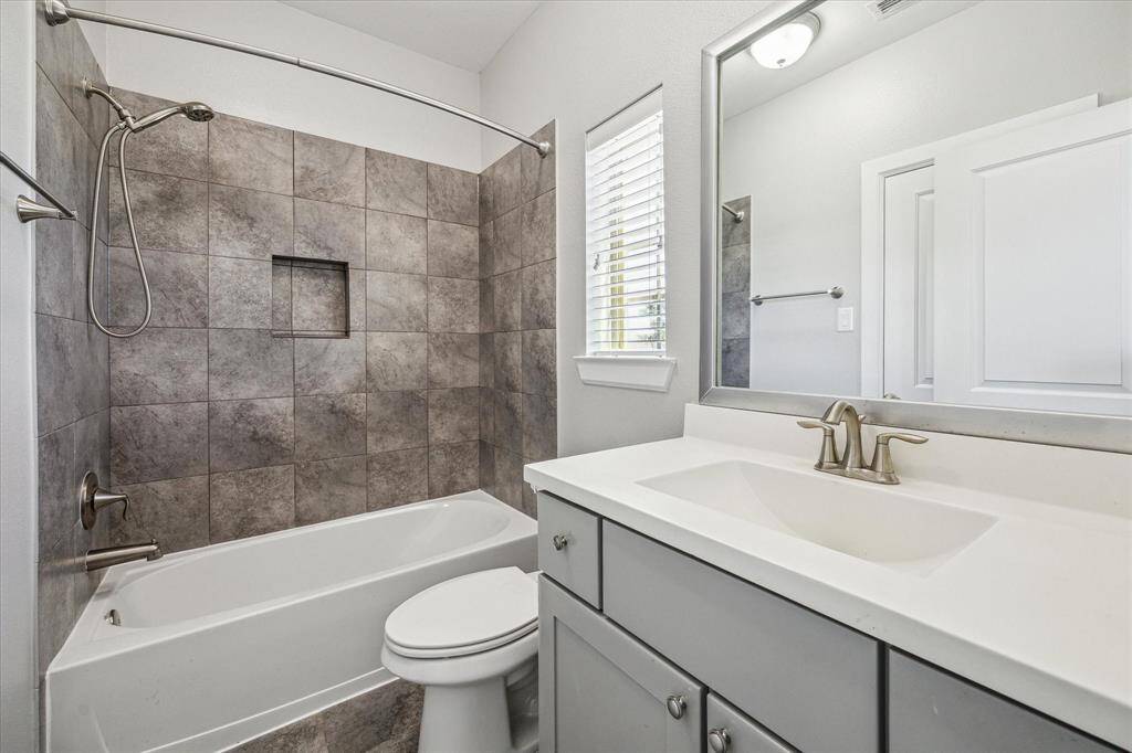 This ensuite offers guests a private escape with a single sink vanity with a framed mirror and vanity lights above along with a fully tiled tub/shower enclosure.