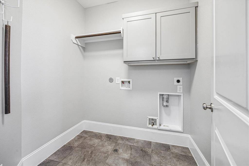 The utility room offers built-in cabinets for household storage, a hanging bar for clothes, and both gas and electric dryer connections.