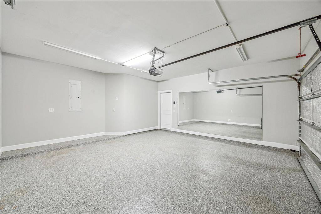 The insulated two-car garage is thoughtfully designed to double as a home gym, featuring durable epoxy flooring, neutral paint, portable A/C, and an expansive wall mirror to enhance your workout space.