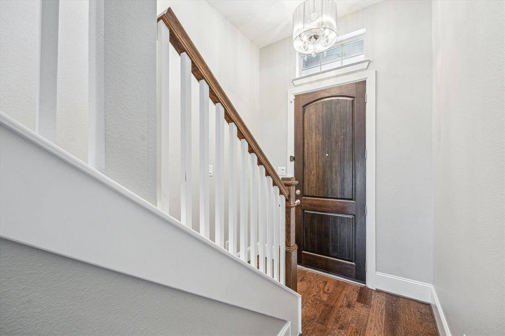 This impressive foyer is a beautiful space to welcome guest into your home with warm finishes including wood flooring, neutral paint and chic overhead lighting.
