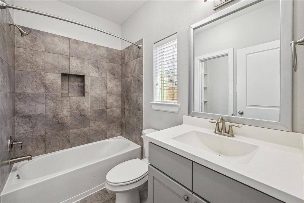 This 1st-floor ensuite offers a modern single sink vanity and a fully tiled tub/shower enclosure.