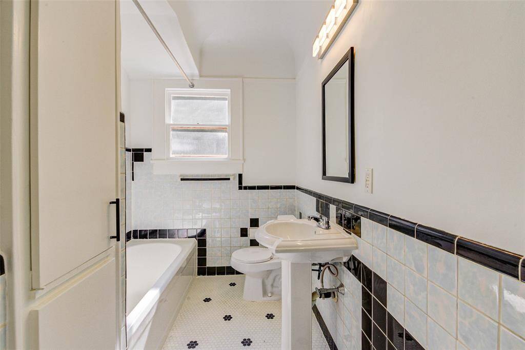 Full bathroom still has original, charming tile. Pedestal sink with new mirror and newvanity lighting. Built in storage for toiletries and more
