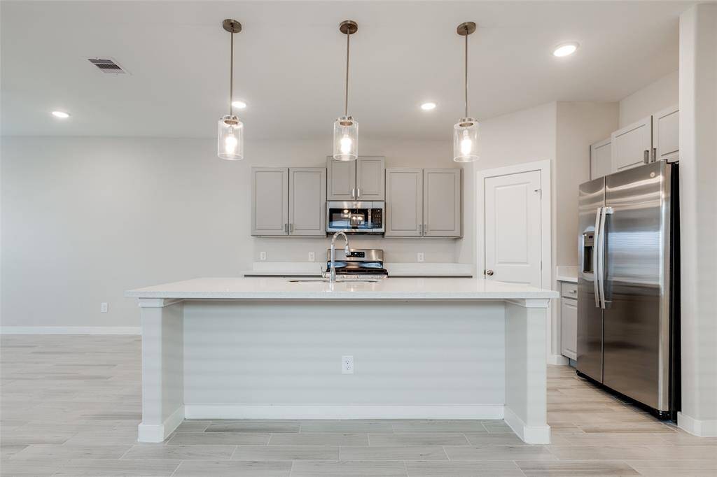 Bright and modern kitchen with quartz counters, gas range, and pantry—clean, fresh, and lightly lived-in. Open flow to living area. Applicances are included in the rental price.
