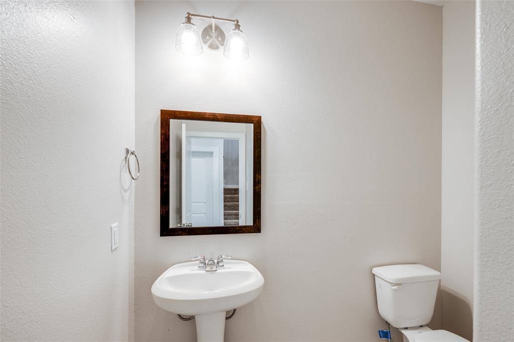 Convenient downstairs half bath with pedestal sink, brushed nickel accents, and modern lighting.