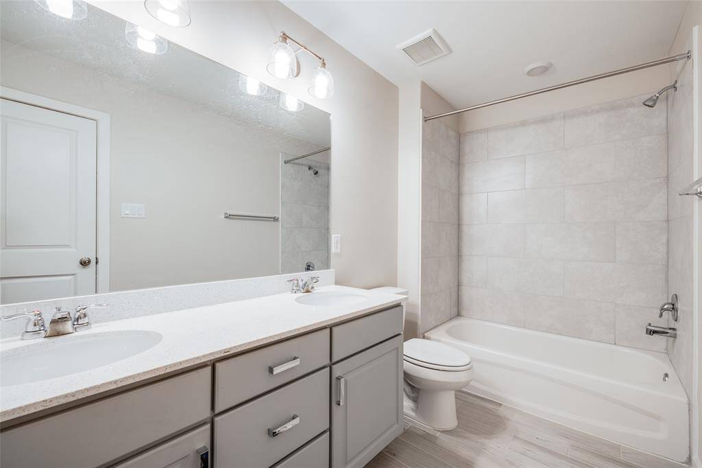 Upstairs shared bath with double sinks and quartz countertops—easily serves the secondary bedrooms.