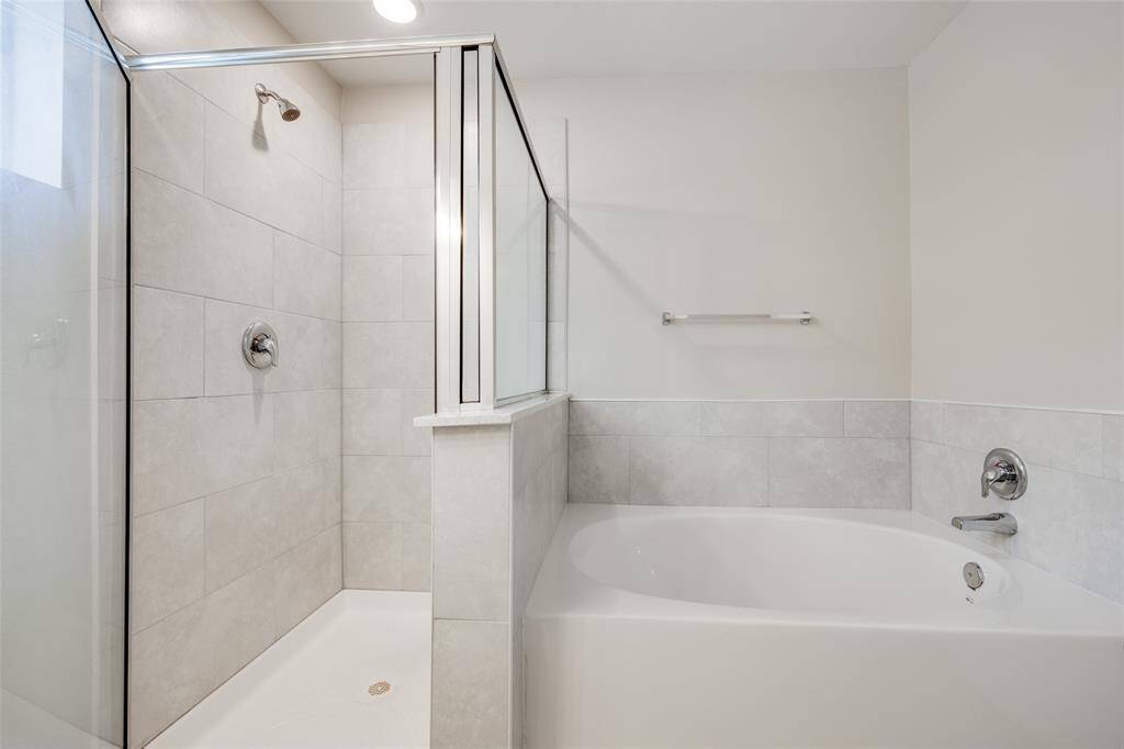 Ensuite bathroom features a soaking tub and glass-enclosed shower.