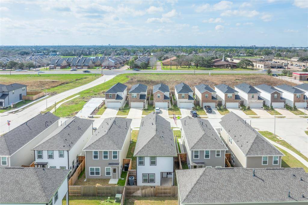 Rear aerial view showcasing uniform design, clean lots, and thoughtful spacing between homes—everything feels streamlined and intentional. Located just minutes from local schools, parks, shopping, and major roadways, this neighborhood offers easy access to everyday essentials without sacrificing peace and privacy.