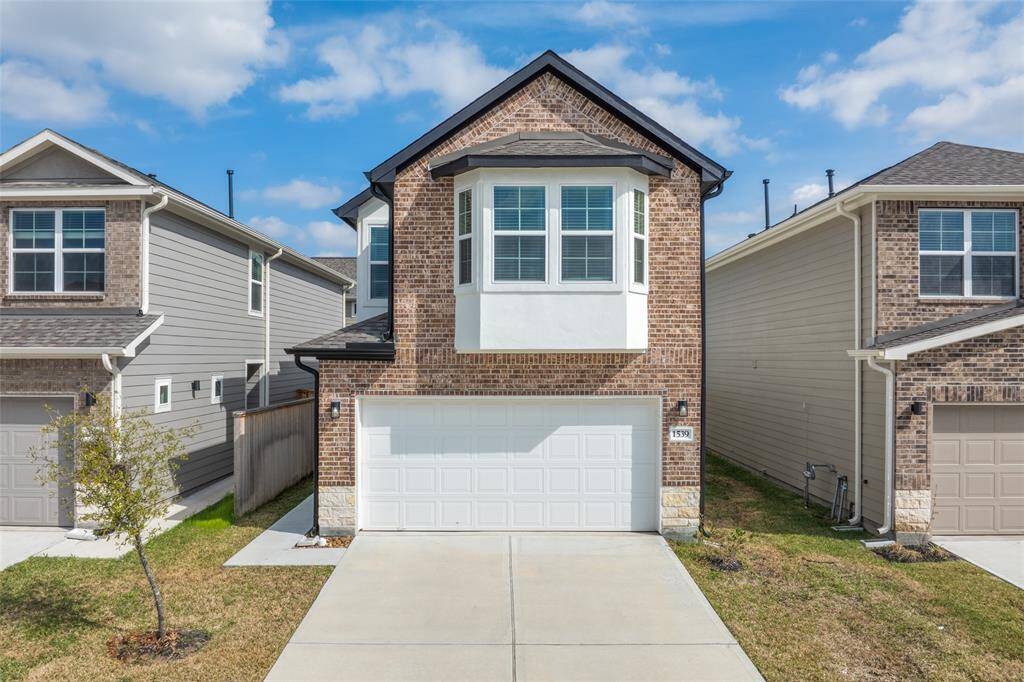 Contemporary curb appeal with brick detail and a standout bay window. Driveway and two-car garage offer plenty of parking.