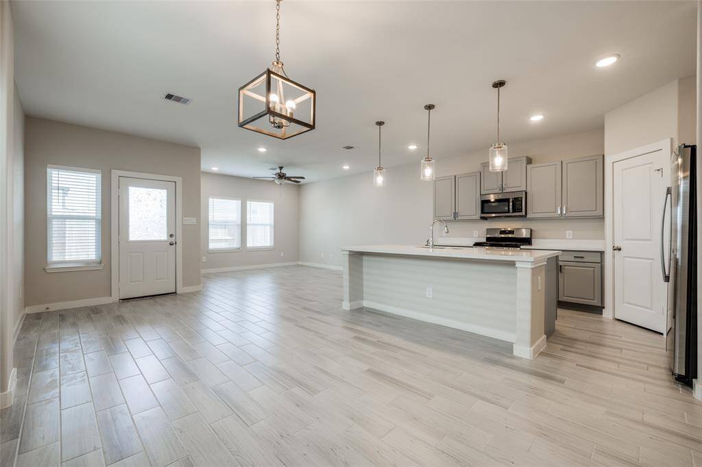 Open plan kitchen with gray cabinets, walk in large pantry, SS appliances, and gas cook top.