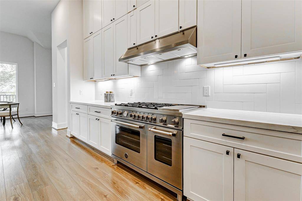 The expansive gas range is a true showstopper, serving as the focal point of the kitchen. The sleek matching vent hood beautifully complements the space, adding both style and functionality.