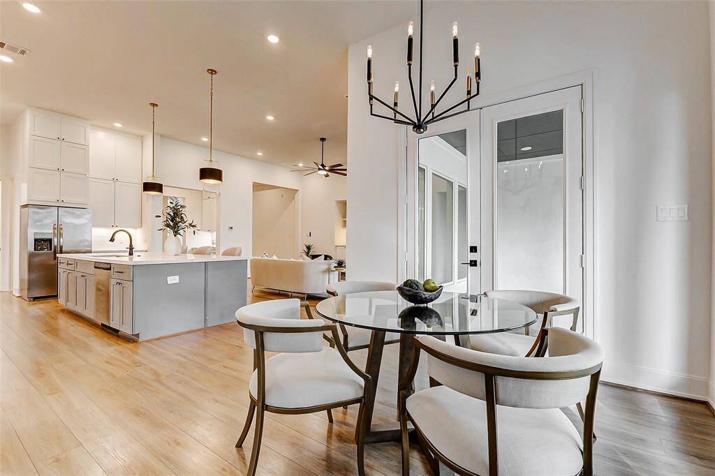 A stunning lighting fixture hangs above, casting a warm glow over the spacious breakfast area. With ample room for a table and chairs, this charming space offers a relaxed, informal setting for everyday meals.
