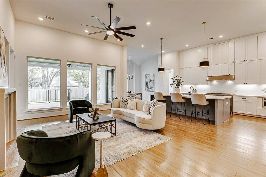 Let your gaze wander to the picture windows that line one wall of this inviting living room, offering breathtaking views of the stunning backyard. With generous space for seating and entertaining, this room is designed for both relaxation and gathering, featuring wood-look floors, a sleek modern ceiling fan, and recessed lighting that enhances its warm ambiance.