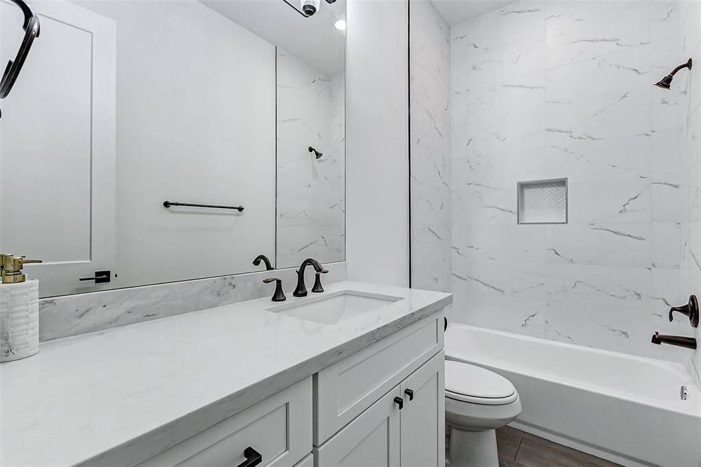 This home includes 3 full bathrooms, each thoughtfully designed with upgraded white cabinetry, coordinating white countertops, and oil-rubbed bronze fixtures. This bathroom features a beautifully tiled tub/shower combo, adding both style and functionality.