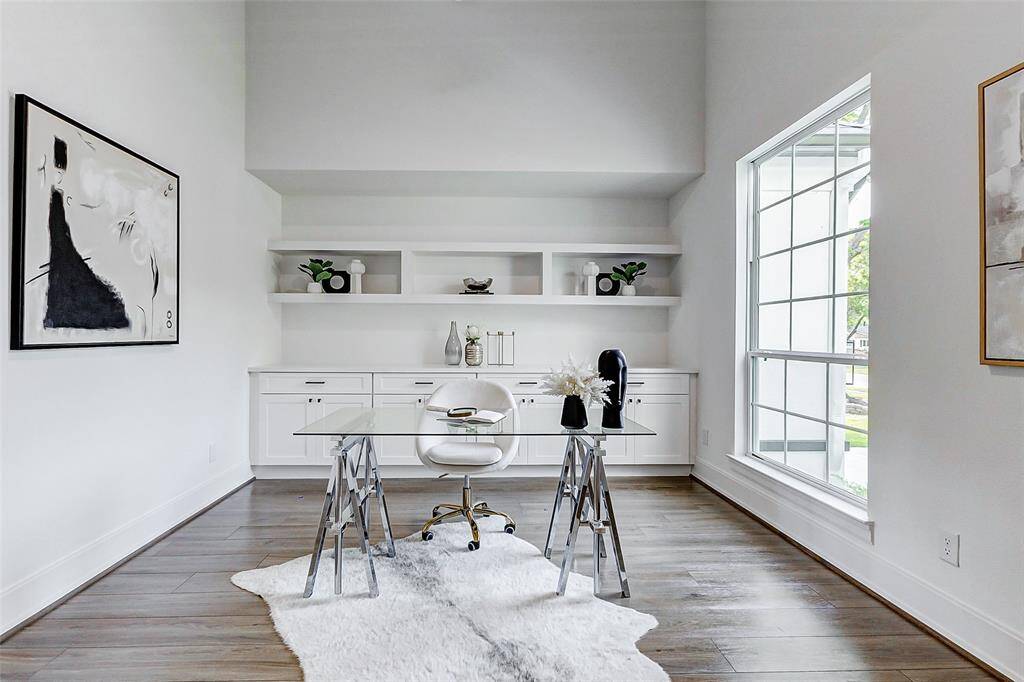 Just off the entryway, you'll find a sophisticated private study featuring custom built-in cabinetry and shelving. Highlights include wood-look flooring, designer paint, upgraded baseboards, and soaring ceilings—blending elegance and practicality in a beautifully designed workspace.