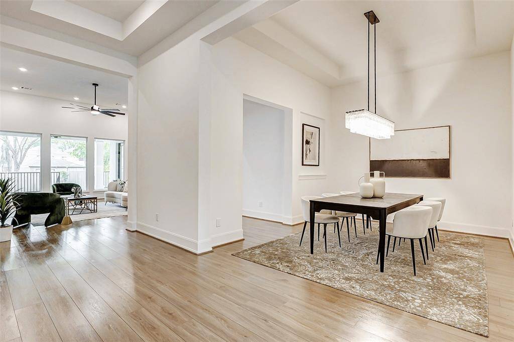 Just beyond the private study lies an elegant formal dining room, beautifully appointed with wood-look flooring, substantial baseboards, and a sophisticated tray ceiling that adds architectural interest. A striking light fixture serves as a stunning focal point, setting the scene for memorable gatherings.