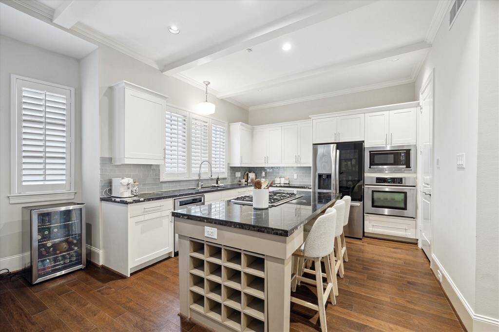This open kitchen has clean lines and a tall ceiling.  The island has seating, an electrical plug, and storage.  Granite and stainless steel throughout.  This is the kitchen you have always wanted (but you just did not want to live through a renovation).