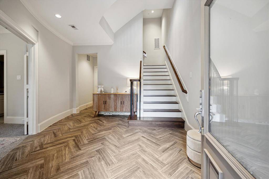 This spacious foyer boasts a herring bone pattern wood floor that adds an old fashioned elegance to the space.  The left side of the photo shows the entrance to the ground floor bedroom.