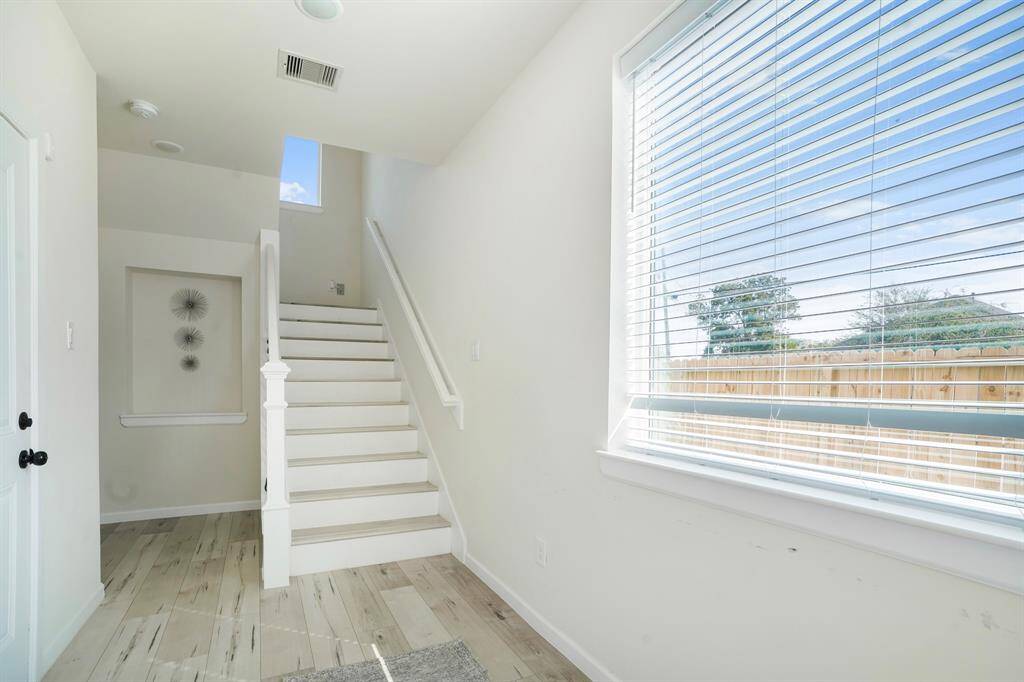Entering into the home you will be greeted with a huge glass window flowing with natural light. The door on the left is leading to the garage. Beside the stairs and to the left is the first story bedroom with a full bath.