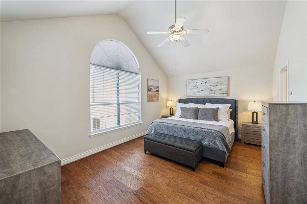 Third-floor primary bedroom with high ceilings, engineered hardwood floors, a large window, and two walk-in closets.
