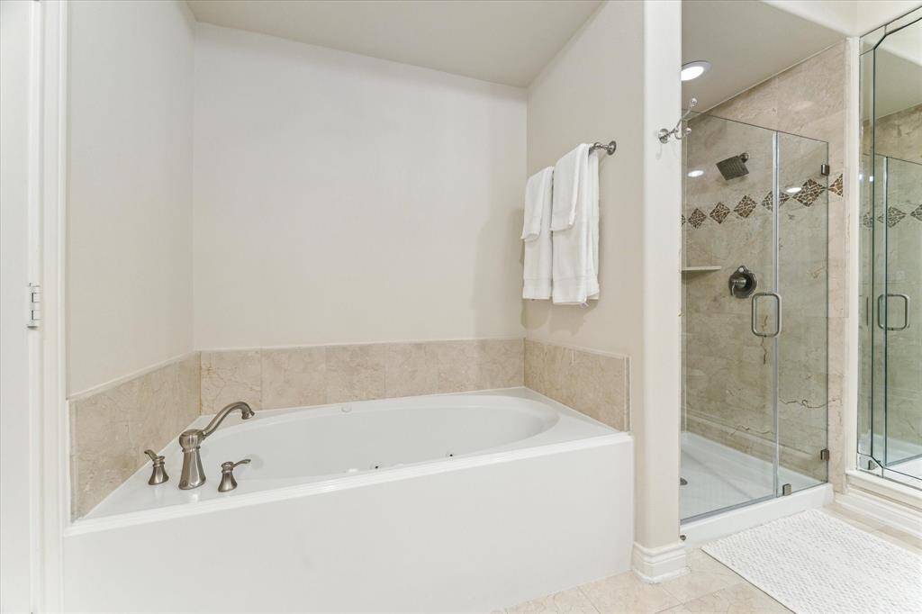 Primary bathroom has a large soaking tub and a separate walk-in shower with glass door.