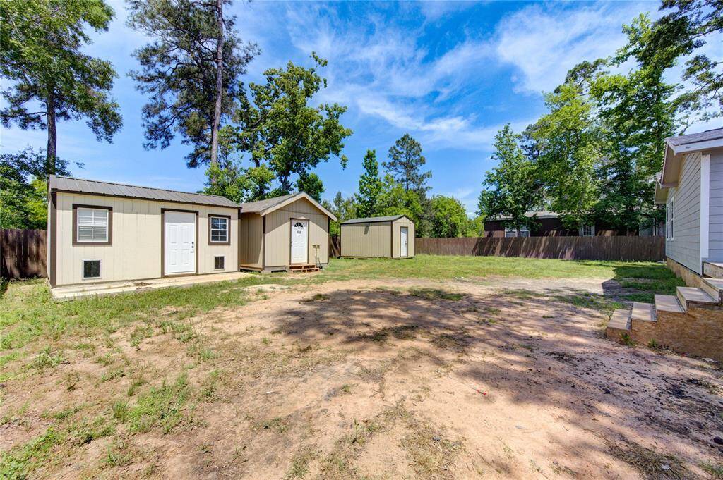 This spacious backyard features two storage sheds and a fenced perimeter, offering ample space for outdoor activities and storage. Surrounded by mature trees, it provides a serene and private setting.