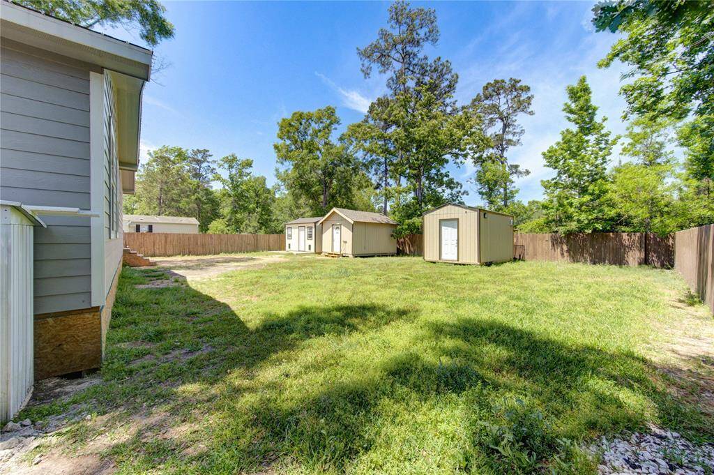 Spacious backyard with well-maintained lawn, two storage sheds, and a wooden privacy fence, providing ample outdoor space in a tranquil setting.