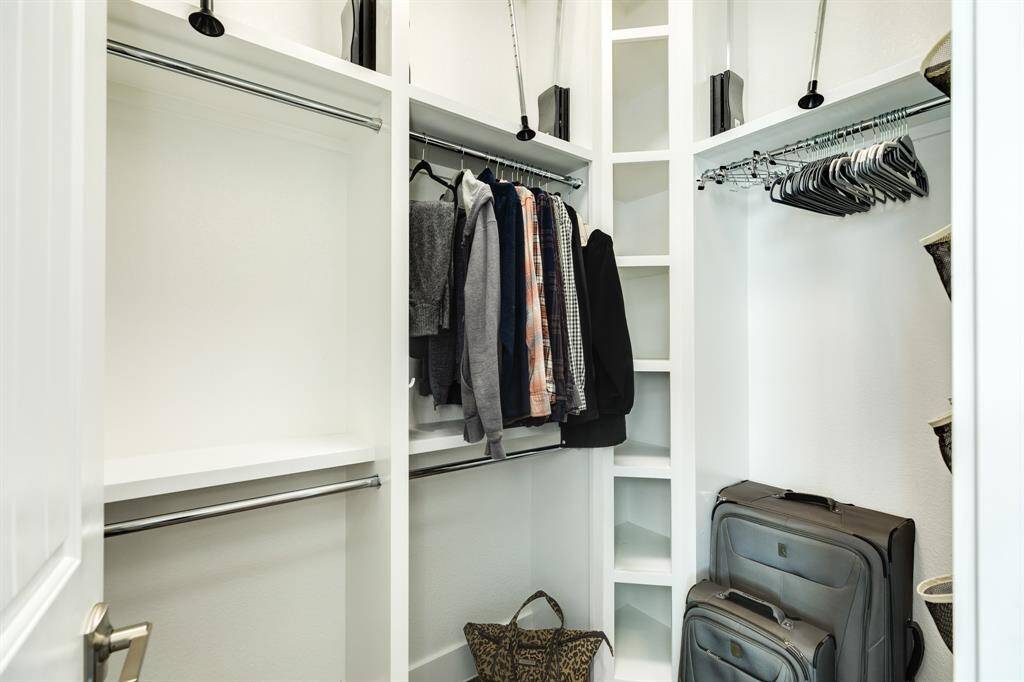 PRIMARY WALK IN CLOSET HAS DUAL SHELVING AND CUSTOM HANGING CLOTHES RODS