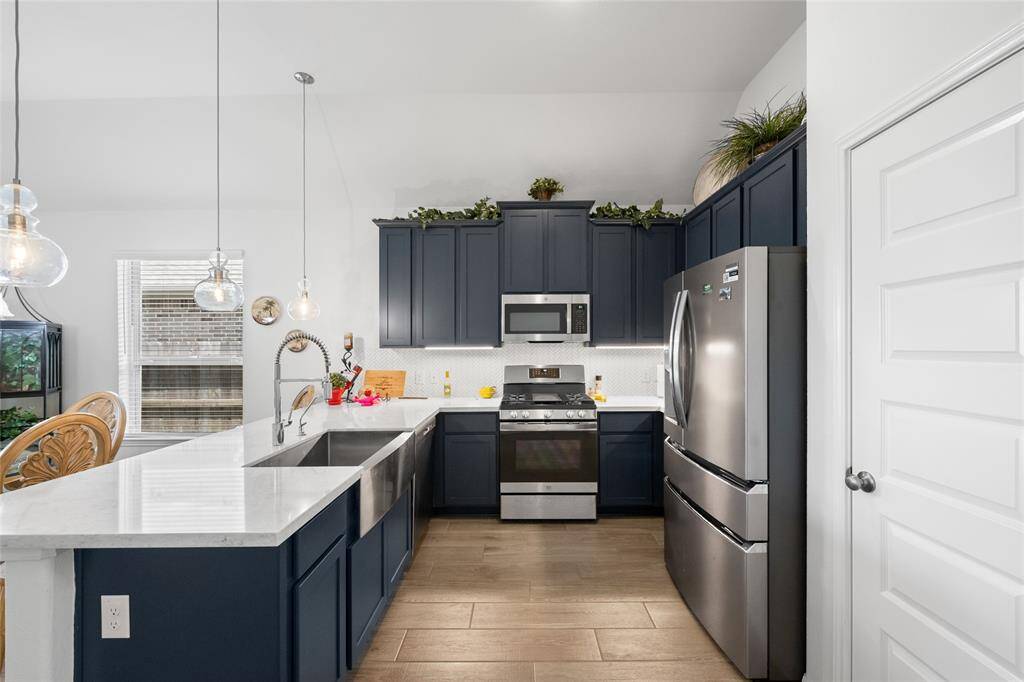 The beautiful kitchen features stainless steel appliances, Quartz countertops and a farmhouse style sink.