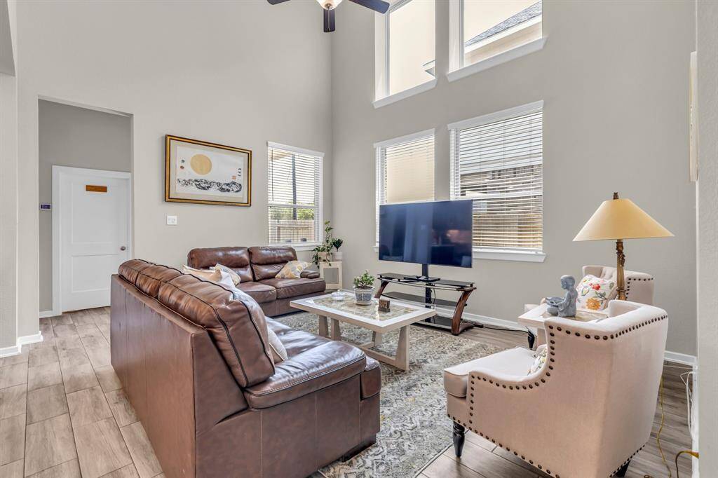Large windows invite in natural light, highlighting the stylish flooring and open layout.