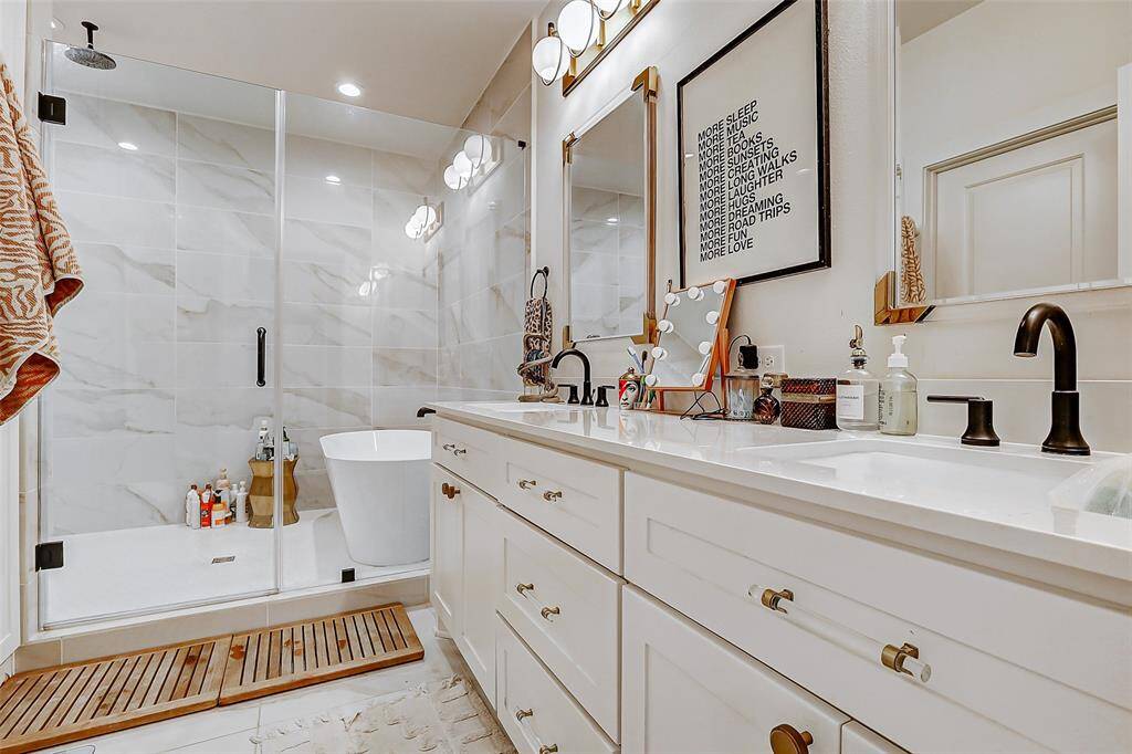 This spa-inspired primary bath showcases designer lighting, sleek tile flooring, and a luxurious walk-in shower that includes a separate soaking tub—creating a true retreat. Quartz double sinks and modern fixtures complete the elegant look.