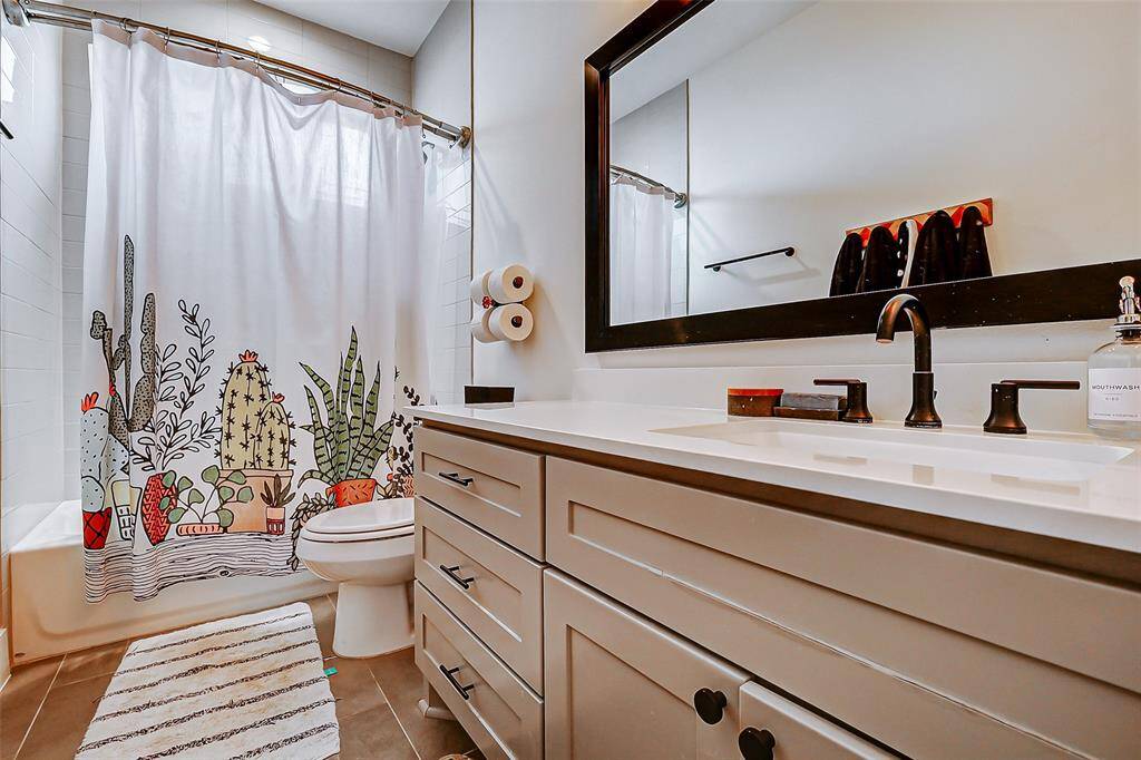 First floor ensuite bathroom to a secondary bedroom features tile flooring, quartz sink countertop, and shower/tub combo.