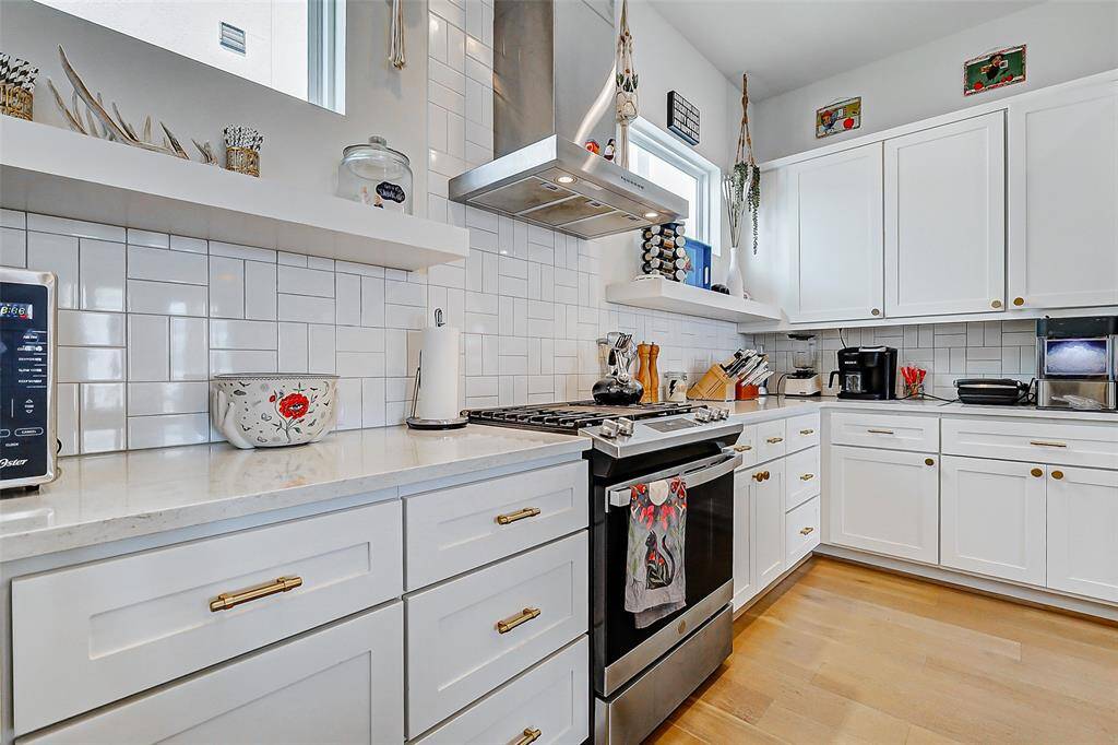 The modern kitchen impresses with quartz countertops, sleek cabinetry, and elegant gold hardware—blending style and function in a bright, open layout perfect for everyday living and entertaining.