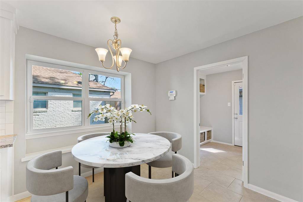 Charming breakfast area that opens to the kitchen, perfect for enjoying everyday meals. Featuring a decorative light fixture, tile flooring, and a large window that brings in natural light. The built-in bench seat adds both charm and functionality to this inviting space. Behind this room is the mudroom and the door that leads out to the 2 car garage.  Note: this photo has been virtually staged.