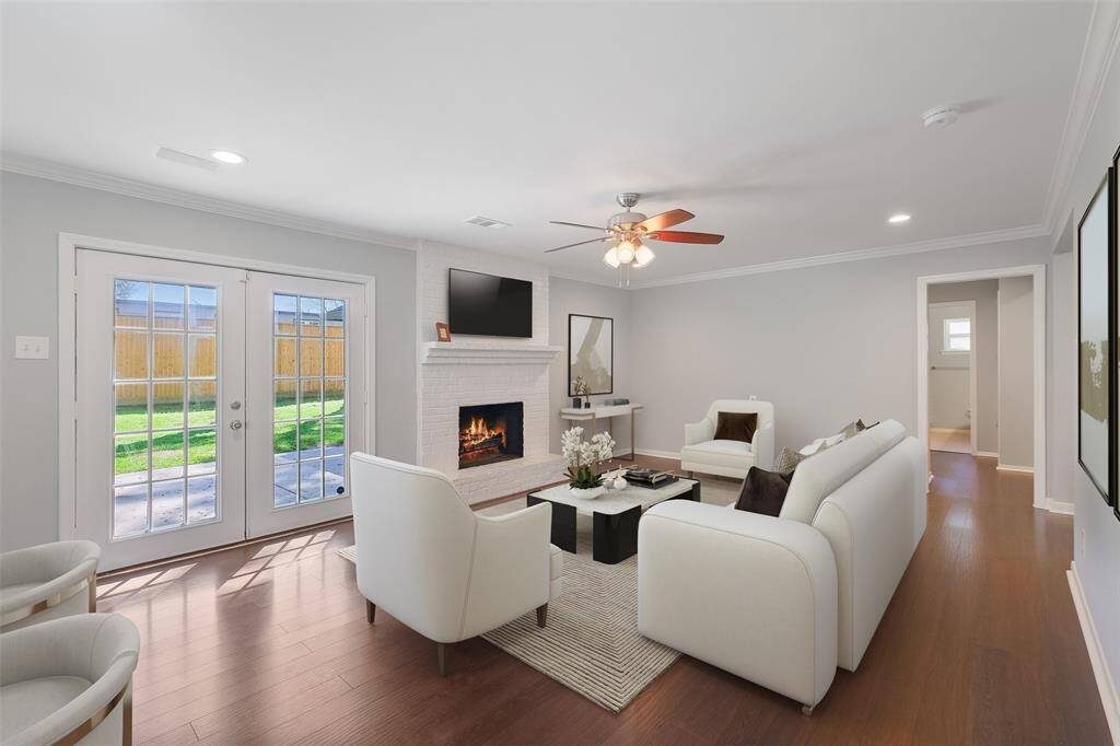 This spacious family room offers flexible furniture arrangements for any lifestyle. Features include a freshly repainted and scraped wood-burning fireplace (2024), engineered hardwood floors, recessed can lights, and crown molding. Large French doors lead to the backyard patio, while ceiling speakers and a ceiling fan/light fixture enhance the room's comfort and functionality. Note: this photo has been virtually staged.