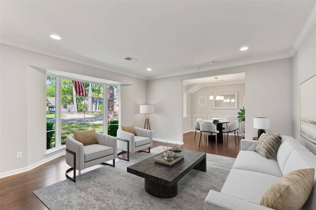 Light and bright formal living room features an open floor plan that seamlessly flows into the formal dining area, perfect for entertaining! Highlighted by engineered hardwood floors, a double-paned bay window offering views of the front yard, crown molding, and recessed can lighting. This versatile space could easily be transformed into a formal dining room or playroom to suit your needs. Note: this photo has been virtually staged.