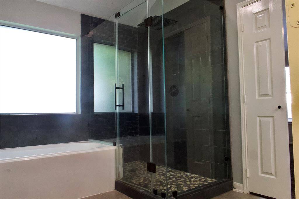 The spacious walk-in shower features a large rain showerhead.