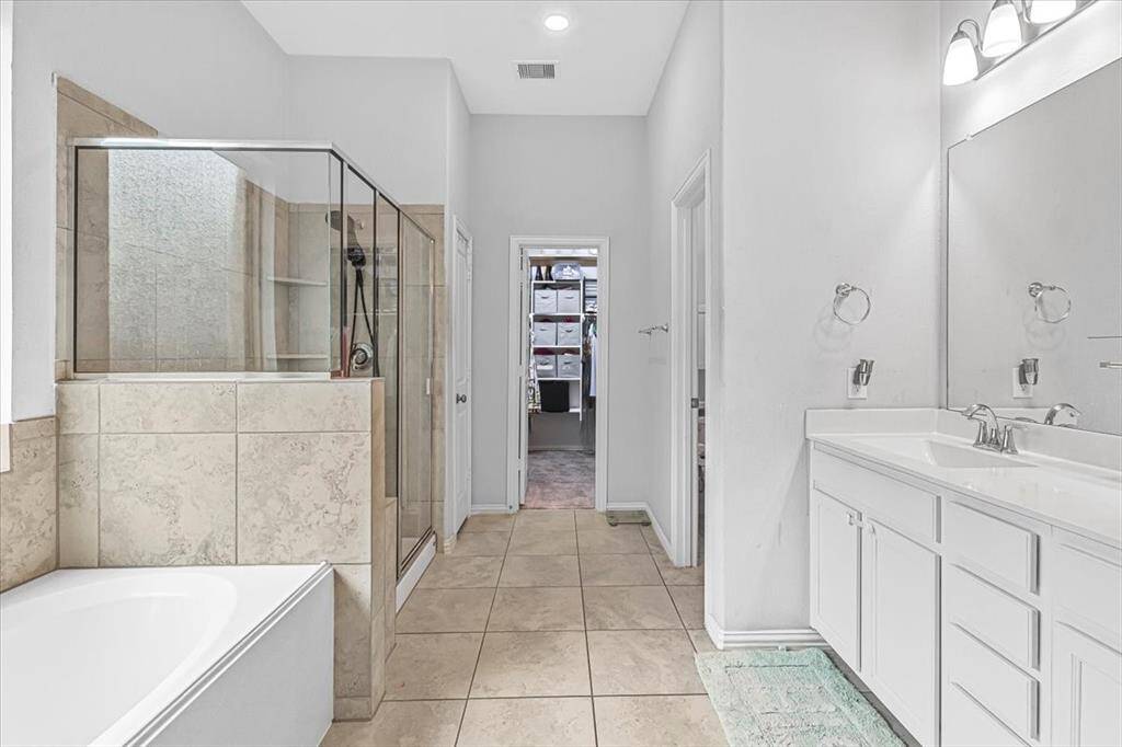 Luxurious en-suite bath featuring dual vanities, soaking tub, separate shower, and spacious  walk-in closet.