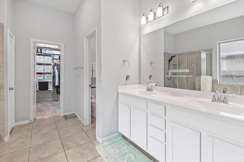 Luxurious en-suite bath featuring dual vanities, soaking tub, separate shower, and spacious  walk-in closet.