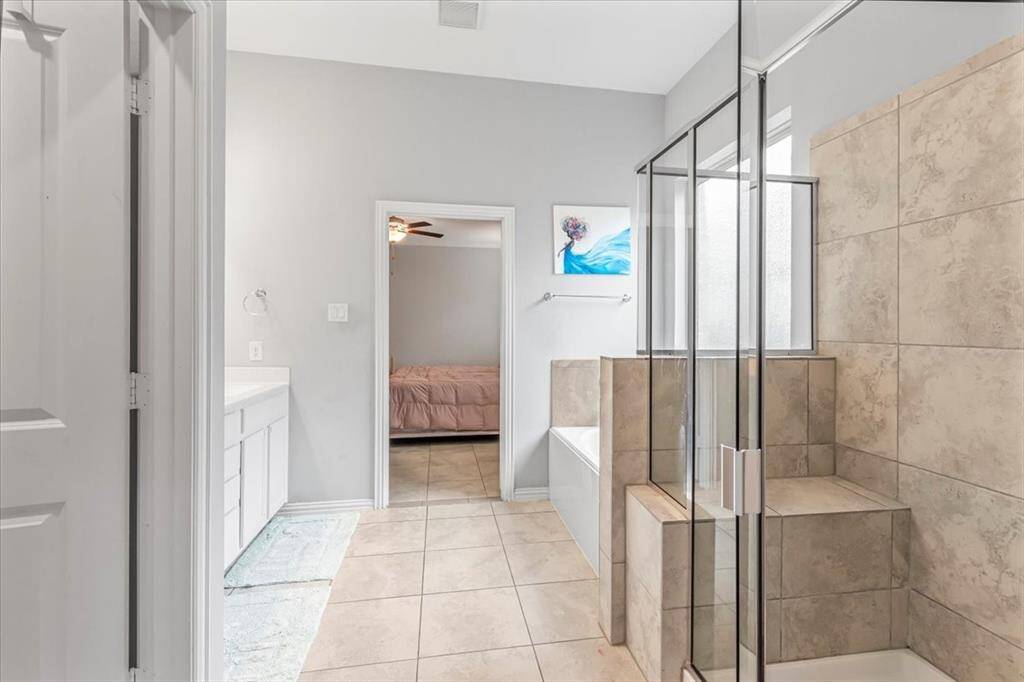 Luxurious en-suite bath featuring dual vanities, soaking tub, separate shower, and spacious  walk-in closet.